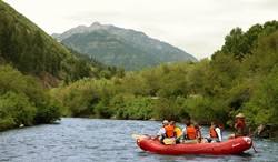 A half dozen people going down a river on an inflatable raft