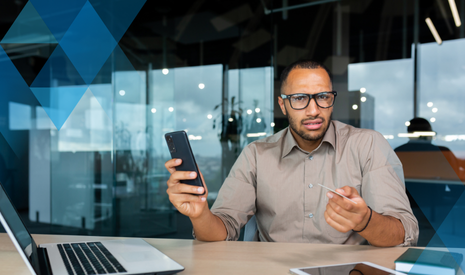 man in office with laptop, credit card, and cell phone looking confused