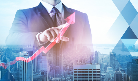 man in dark suit pointing to graph with upward arrow