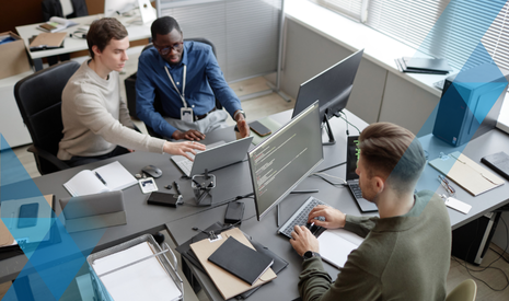three millennial men stilling at a desk table with computers